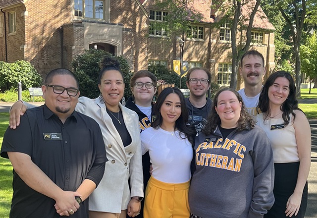 PLU Admission Counselors pose together on campus outside on a sunny day