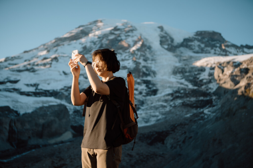 Student stands on a mountain and takes a photo.