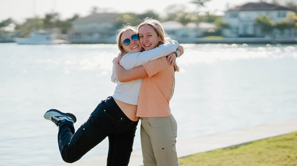 two women hug in front of the ocean in Florida.