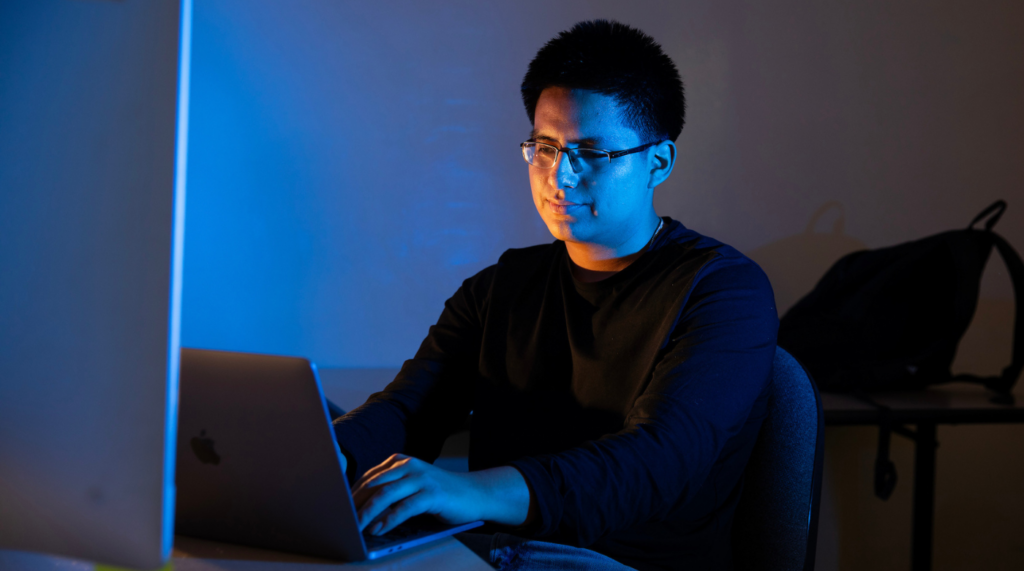 Student works on a laptop with blue light.