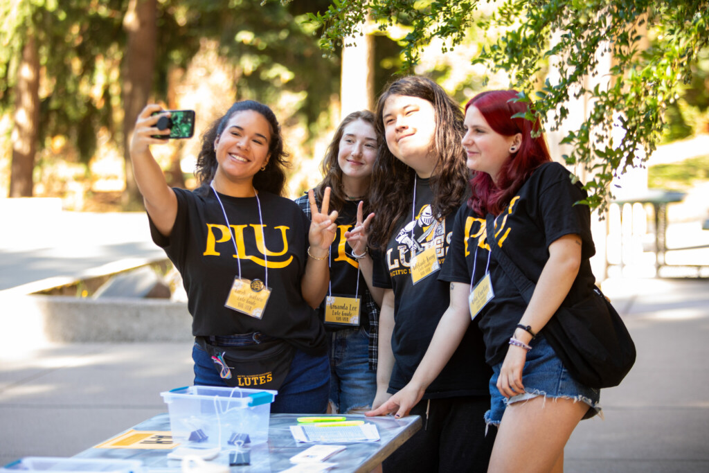 Students take a selfie outside wearing matching PLU shirts.