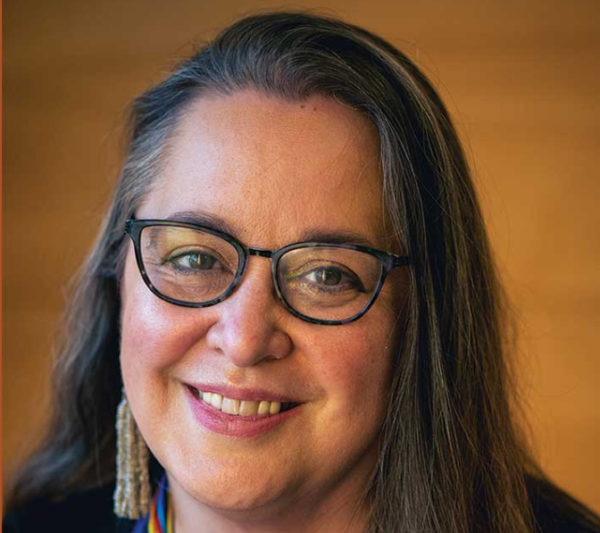 Cynthia Leitich Smith, a woman with glasses and long hair and hanging earrings