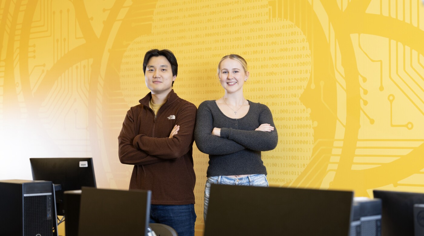 Two students stand in a computer science classroom