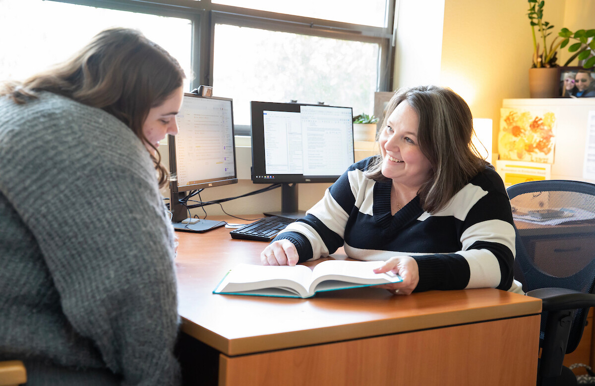 Professor Tiffany Artime sitting at her desk talking to a student.