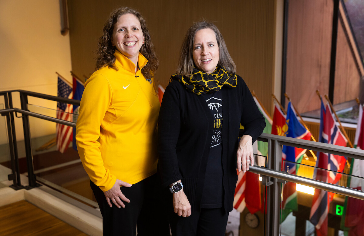 Dr. Ann Auman and Dr. Bridget Yaden pose in front of international flags.