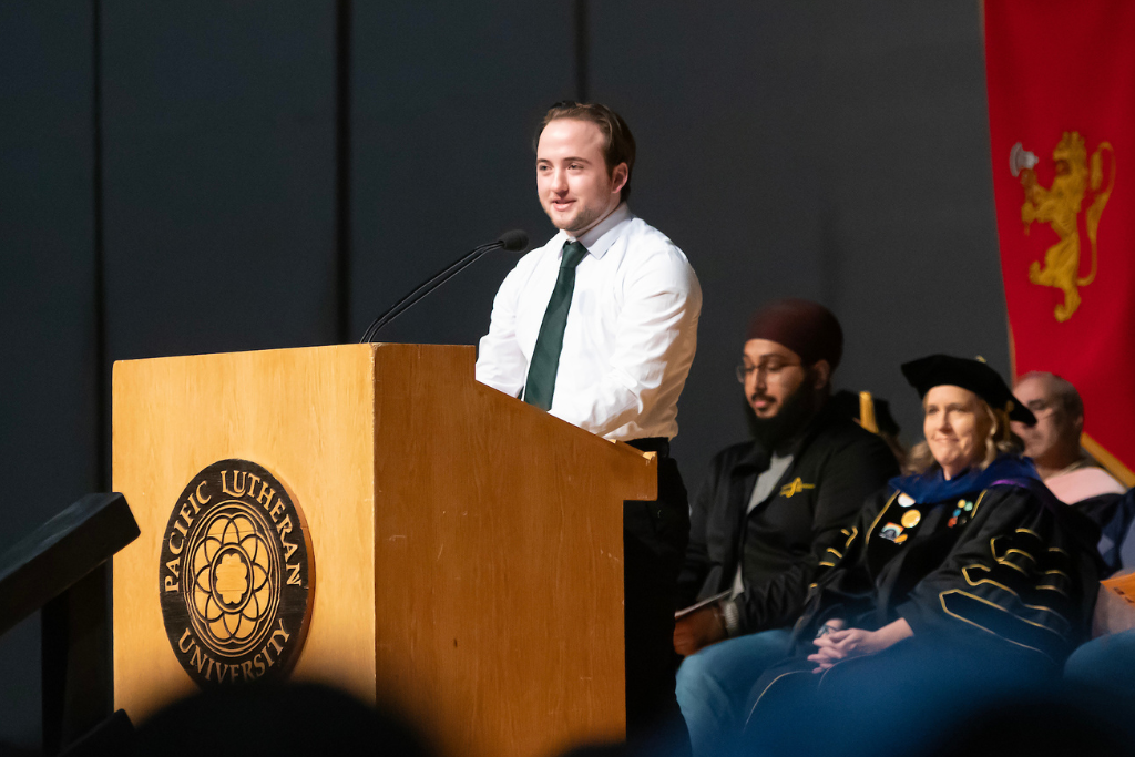 Student stands at a podium and speaks to students.