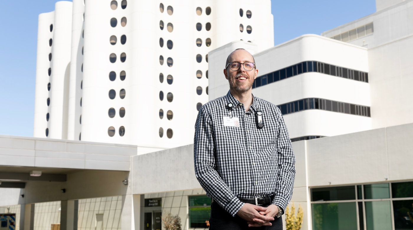 Professor stands in front of Tacoma Hospital and smiles