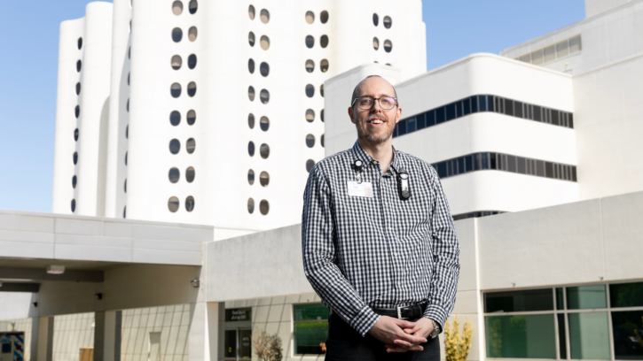 Professor stands in front of Tacoma Hospital and smiles