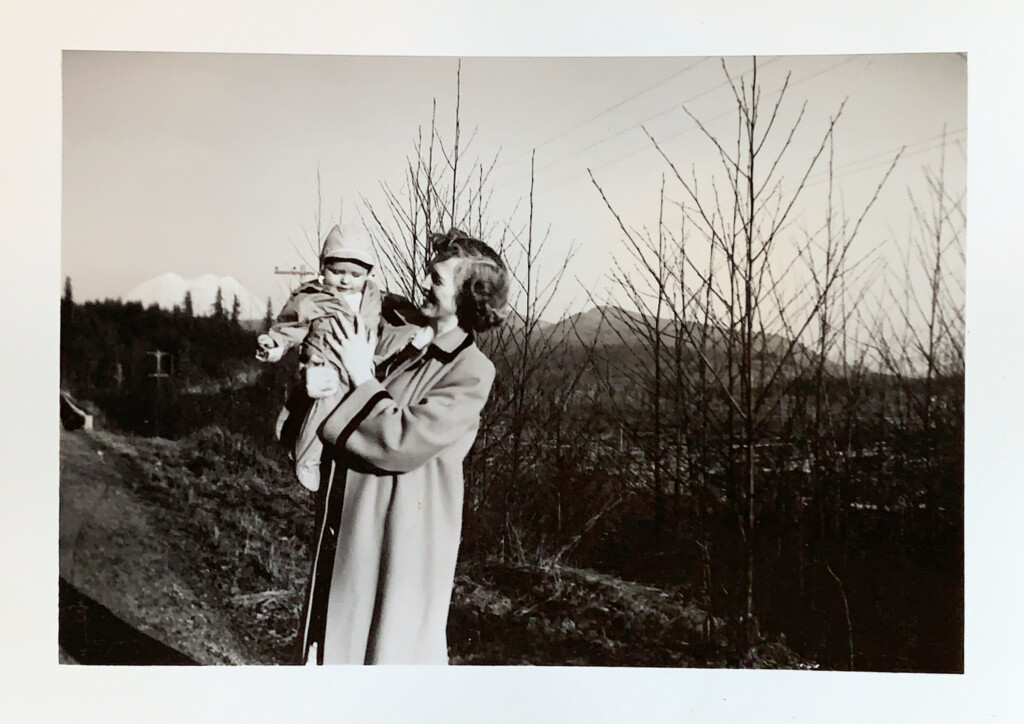 Old black and white photograph of a woman holding a baby outside