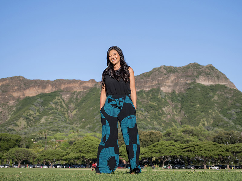 Cheri Souza standing in green grass with a mountain range in the distance behind her.