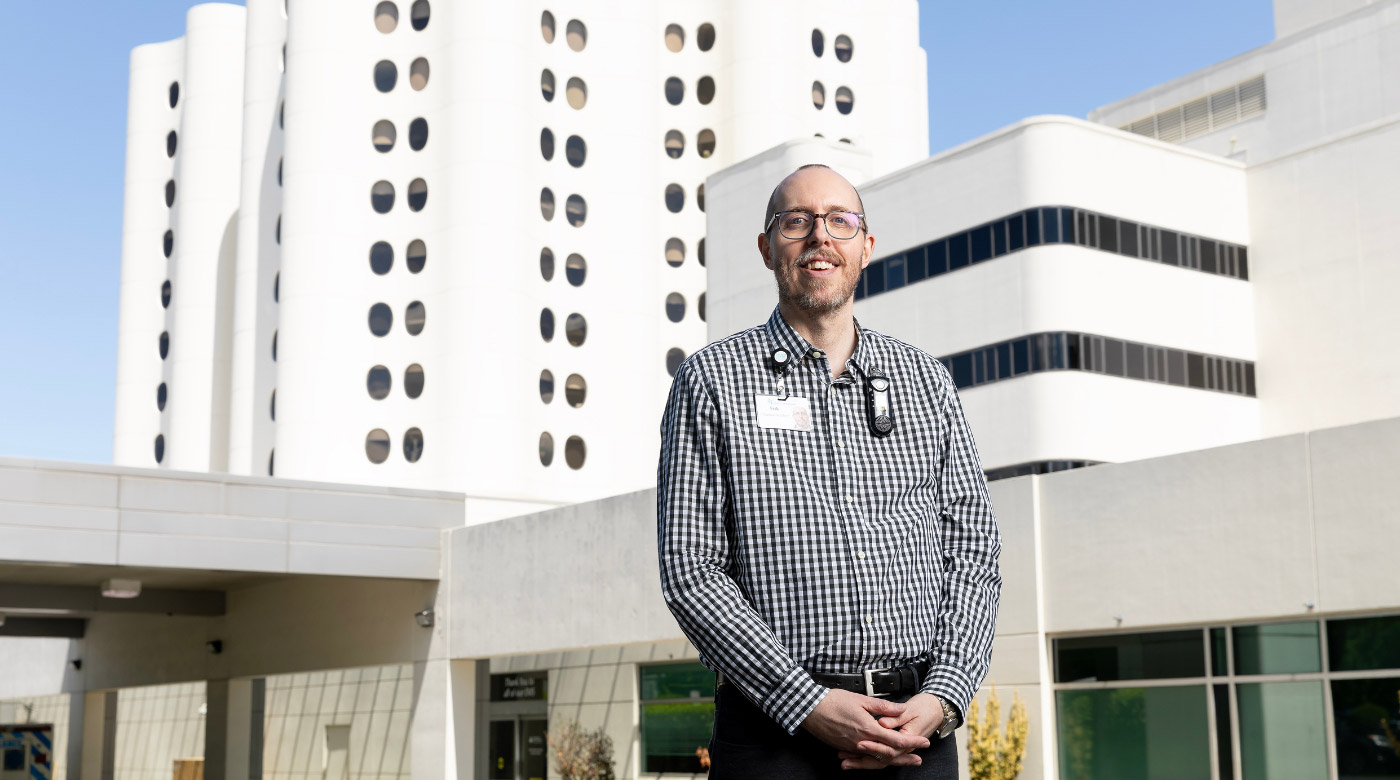 Professor stands in front of Tacoma Hospital and smiles