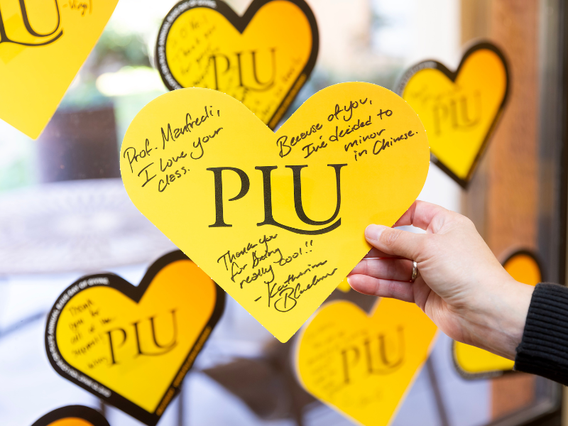 A close up of a person holding a PLU gold heart.