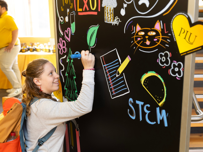 A student draws on a public mural.