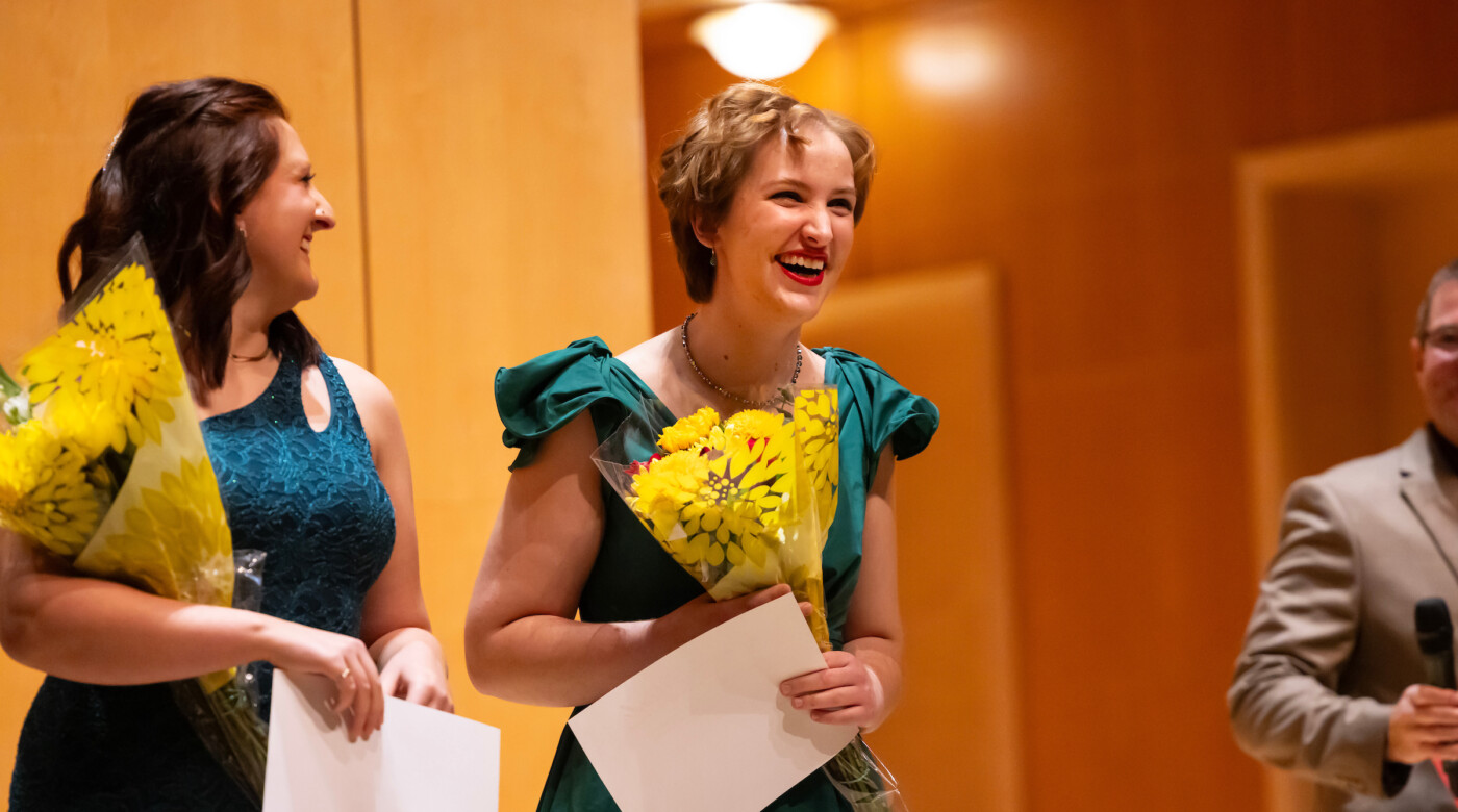 Two finalists smile while receiving their prizes.