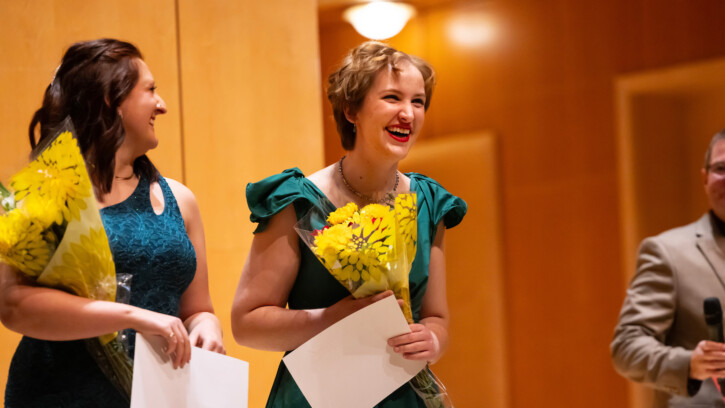 Two finalists smile while receiving their prizes.